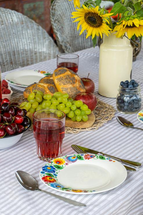 Łowicki talerz w otoczeniu owoców i dekoracji stołu.